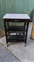 Front and side angle view of the bar cart showing the polished quartz top, drawer, and bottom shelves with bottle holder shelf.