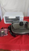 White Black & Decker toaster oven next to black square electric skillet on red tablecloth