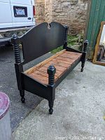 Full view of vintage wooden deacon's bench showing turned legs, black painted back and sides, and natural wood plank seat.