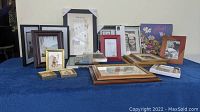 Variety of frames and framed pictures, photo album on table