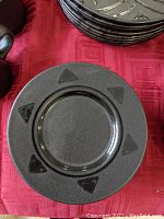 Close up photo of a small dark gray saucer plate with embossed triangular patterns