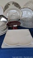 Overall display of assorted platters, bowls and plates arranged on table, showing patterns and styles