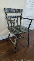 Wooden captain's chair painted in black and grey with a marbled finish viewed from side angle, showing armrest and spindle leg detail.