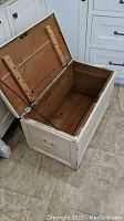 Photo of the wooden box open showing interior, metal support chains, and wood grain inside.