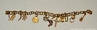 Full-length shot of 10KT gold charm bracelet laid flat showing all charms