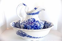 Full view of antique wash basin and matching pitcher with blue floral flow blue decoration.
