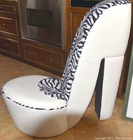 Side profile view of the stiletto shoe chair showing the white and zebra print upholstery and heel shape.