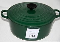 Top-down angle showing green enameled cast iron stock pot with lid, two handles and 'MaxSold 134' sticker.