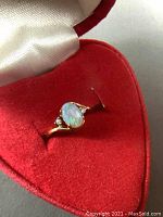 Ring displayed in open red heart-shaped velvet box with white silk interior.