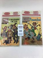 Front view of two sealed comics Wizard of Oz and Pinocchio with original header packaging showing brand Classics Illustrated Junior.