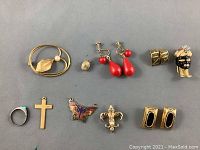 Top-down view of 10 vintage costume jewelry pieces on gray background showing assorted styles and various types including rings, brooches, earrings, and pins.