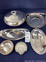 Full set of 8 vintage silverplated servingware pieces shown together on a dark background. Items include trays, bowls, spoons, and a lidded covered dish. Tarnishing and wear visible on surfaces.