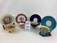 All four teacup and saucer sets displayed with stands in a row against white background
