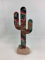 Front view of painted metal cactus sculpture with colorful Southwest style pattern mounted on a stone base