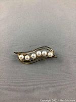 Front view of a vintage sterling silver brooch with six white pearls arranged horizontally.