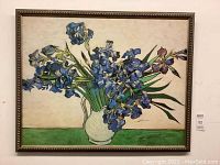 Framed print showing full artwork with frame and visible museum label next to it, displaying Van Gogh's Irises painting in a vase.