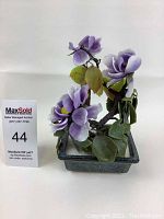 Front view of vintage glass bonsai tree showing purple flowers, green leaves, and ceramic pot.