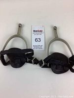 Pair of WW2 military issue stirrups showing metal frame and leather straps with wear.