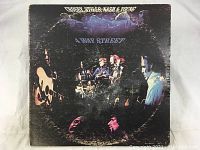 Front cover of the '4 Way Street' album by Crosby Stills Nash & Young, showing the band members in a dark concert setting with signed names.