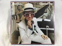 Front cover of Elton John Greatest Hits vinyl record album showing Elton John in white suit and hat.