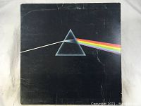 Front cover of Dark Side Of The Moon album showing the iconic prism and rainbow design with some creases and wear