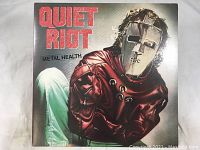 Front of the album cover of Quiet Riot Metal Health showing man wearing metal mask and straitjacket.
