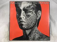 Front album cover showing Tattoo You artwork depicting a man's face with tattoo patterns on an orange background.