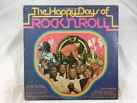 Front cover of The Happy Days of Rock n Roll vinyl LP album displaying colorful graphics and title text.