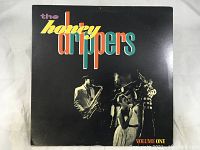 Front cover of The Honey Drippers Volume One vinyl LP showing band members in classic attire and colorful typography.