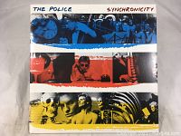 Album cover front showing colorful collage artwork with stripes in blue, red, white, yellow and text The Police Synchronicity.
