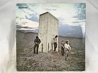 Front cover of 'Who's Next' album by The Who showing band members outdoors near a large concrete slab with cloudy sky background.