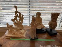 Photo showing all five statues including seated Buddha, female figurine, animal carvings, and head sculpture.