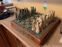 Three-quarter view of chess set on counter showing board, Aztec and Spanish pieces in starting position