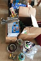 Photo of various boxed and loose Christmas decorations including ceramic jar, snowman figurine, and plaques.