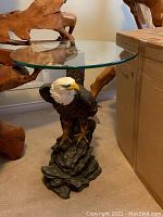 Assembled table showing eagle sculpture base with rock pedestal and glass top from front
