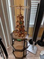 Overall view showing wooden Christmas pyramid on top of octagonal rattan shelf next to speakers