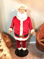 Full front view of life-size Santa figure on round black base