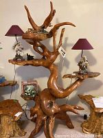 Front view showing entire teak root stand with three attached shelves and decorative items