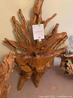 Full front view of teak root chair showing backrest and three root legs.