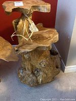 Front and side view of hand carved wooden shelf showing natural wood grain and three tier surfaces.