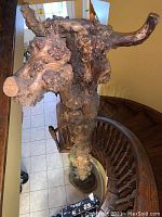 Full view of heavy knotty wood post with a rough and textured surface showing multiple burls and knots, placed near a staircase.