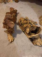 Overall view of both wooden lizard sculptures on a carpeted floor, showing detailed carving and natural wood tones