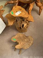 Two wood tree root stands with irregular natural wood tops and root bases on carpeted floor.