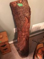 Front view of carved wood wall hanging showing facial carving and bark edges