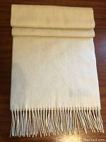 Cream colored wool scarf folded, showing texture and size.