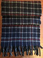 Full length of folded navy plaid scarf showing tartan pattern and fringed ends.