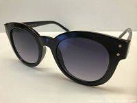 Front angle close-up of black rounded sunglasses with gradient lenses showing gold rivet details on frame