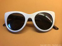 Front view of white framed semi-horned style sunglasses with dark lenses.