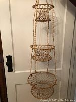 Full view of the three-tier hanging basket made of twisted jute and bamboo with circular bamboo rims and knotted jute basket bottoms.
