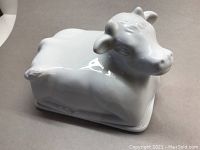White ceramic cow shaped lidded cheese tray from side angle showing glossy surface and shape